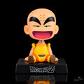 Krillin Dragon Ball Z seated anime bobblehead figure with six forehead dots, yellow orange monk outfit, spring neck and black Dragon Ball Z display base, front view